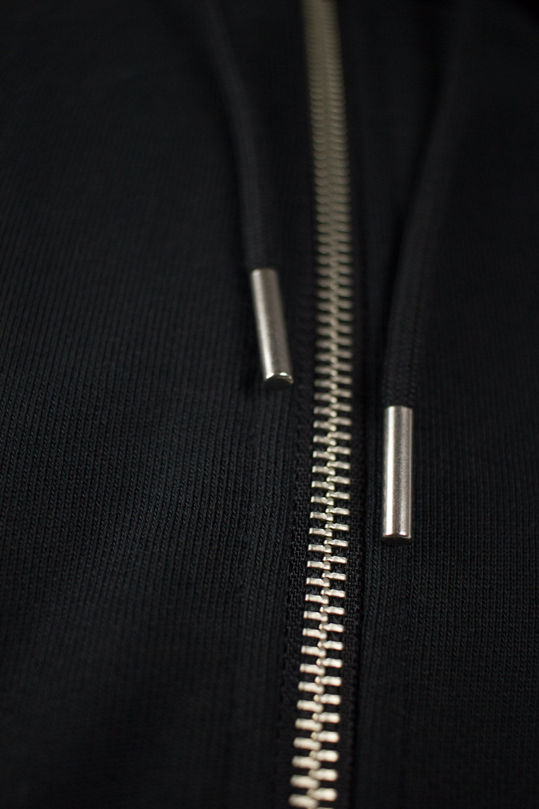 Close up of a Zipper and Drawstrings from black Zip Up Hoodie by The Embroidery Crew