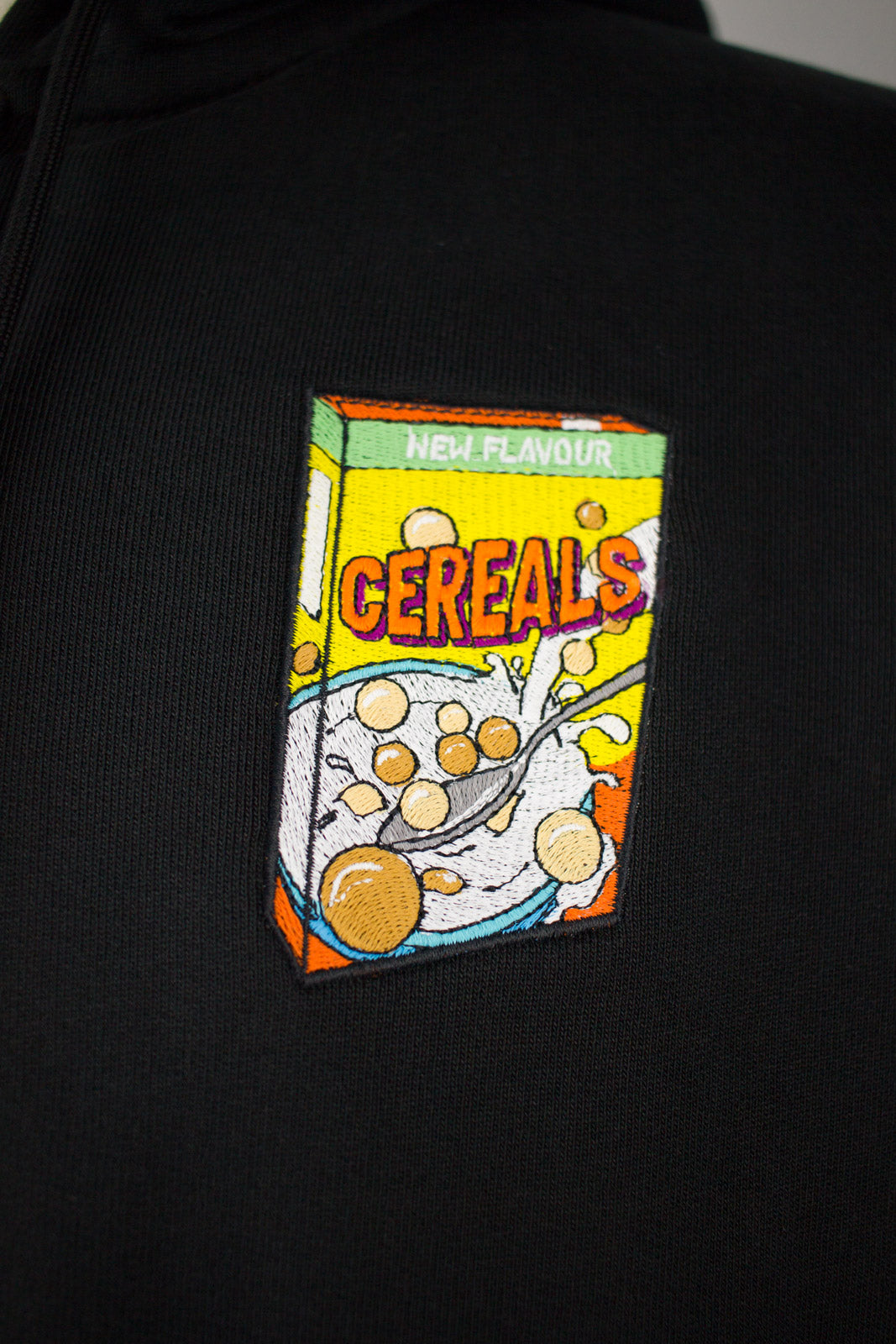 Close up of embroidered cereals design on a black Zip Up Hoodie by The Embroidery Crew
