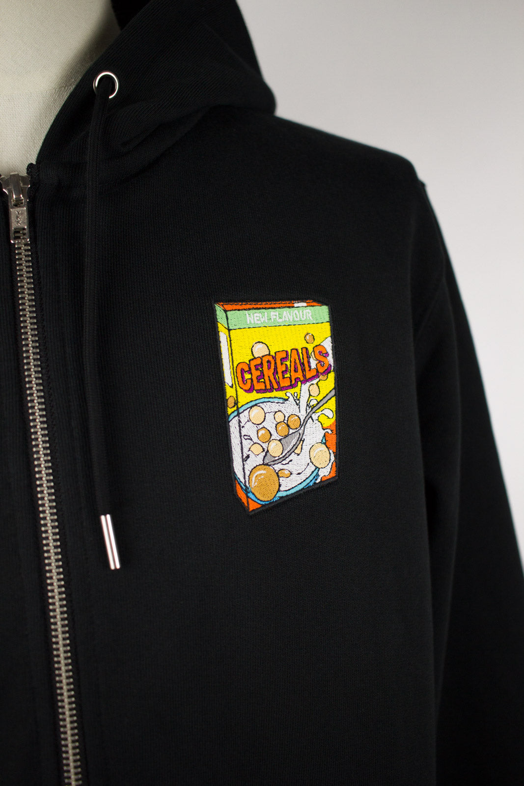 Close up of embroidered cereals design on a black Zip Up Hoodie by The Embroidery Crew