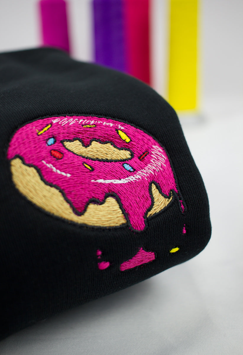 A close up of a embroidered donut on a black sweatshirt