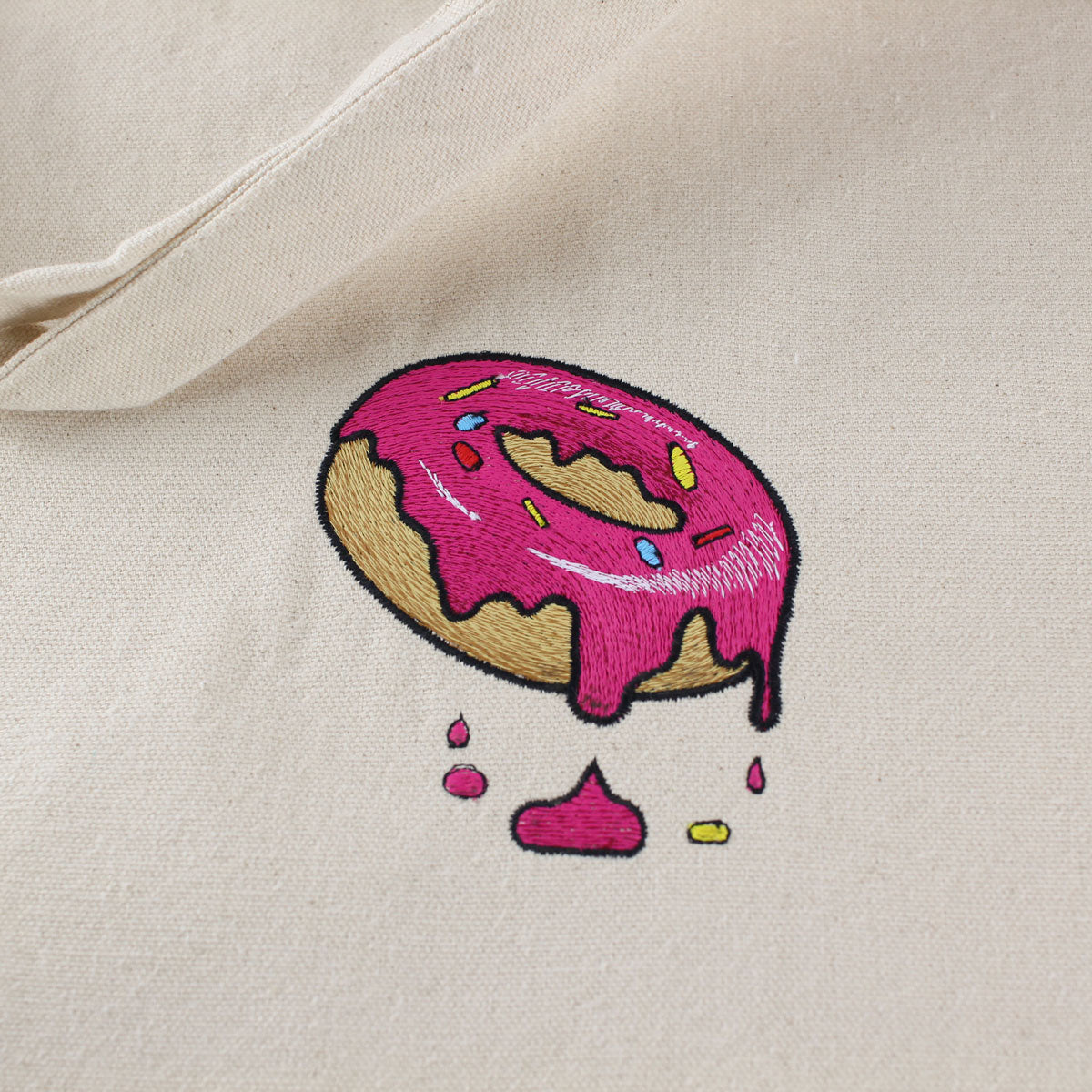 A close up of a natural coloured tote bag with donut embroidery by The Embroidery Crew