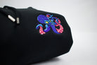 A close up of a folded hoodie with embroidered octopus, vibrant colours, white background