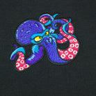 A close up of an embroidered octopus on a black hoodie, vibrant colours