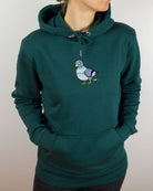 woman wearing a green hoodie with pigeon embroidery