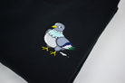 An embroidered pigeon on a black folded sweatshirt